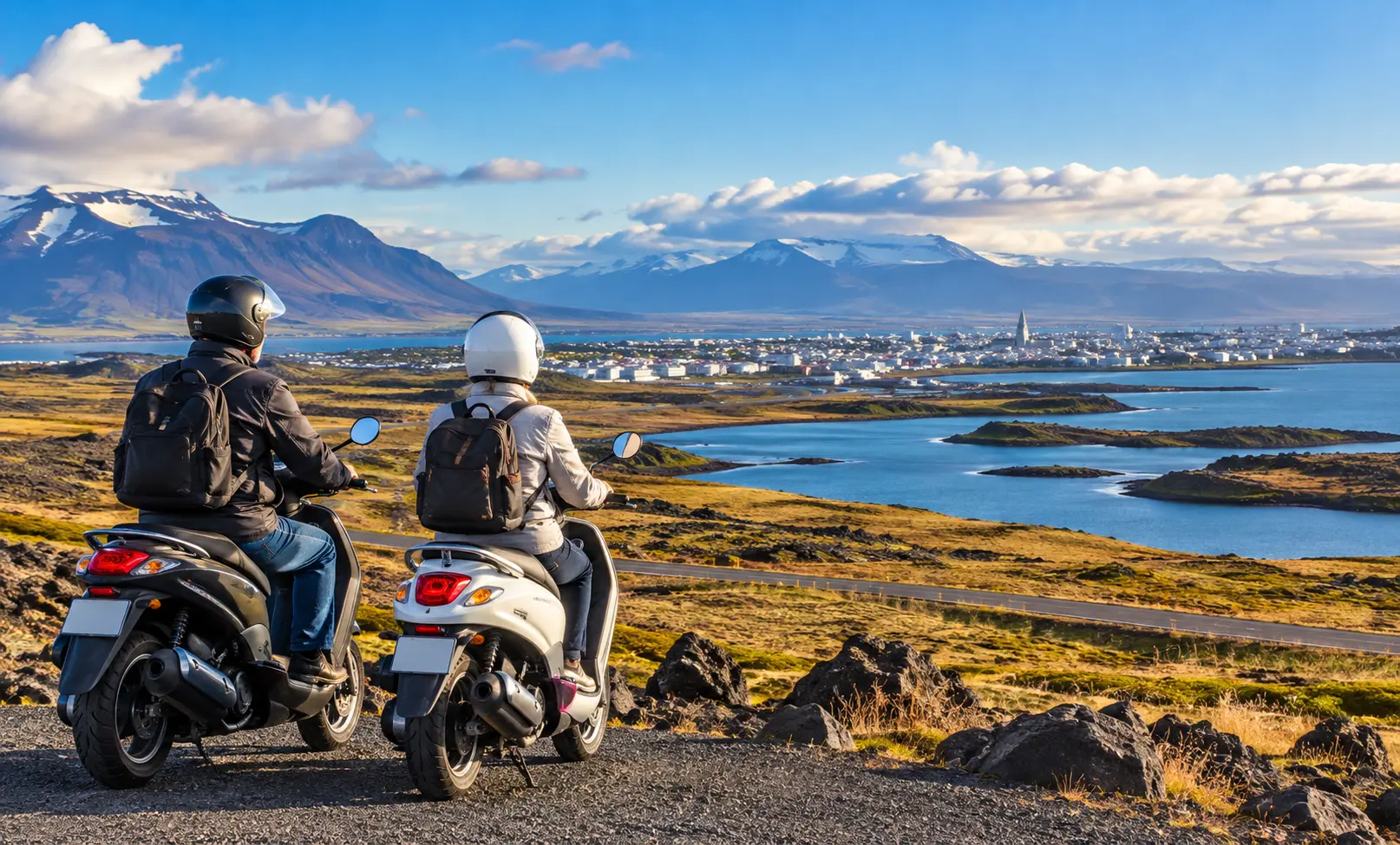 Older couple on scooters overlooking Reykjavík, surrounded by Iceland’s dramatic volcanic landscape, coastline and mountains.