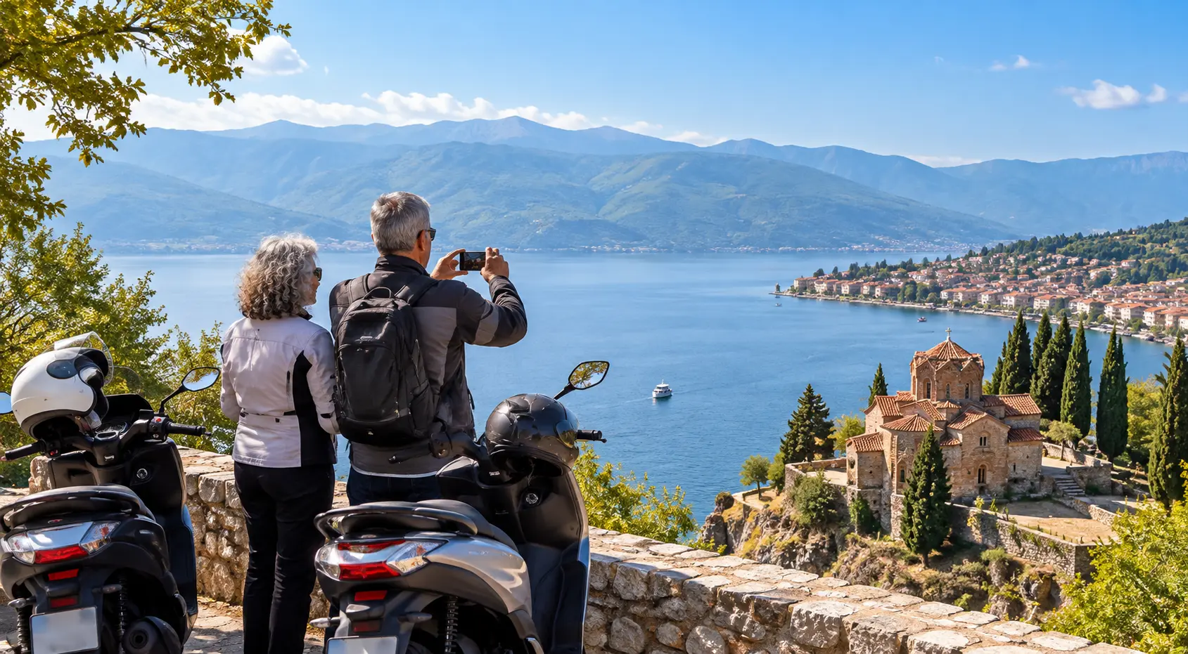 Older couple enjoying the spectacular views over Lake Ohrid beside their rental scooters in Macedonia.